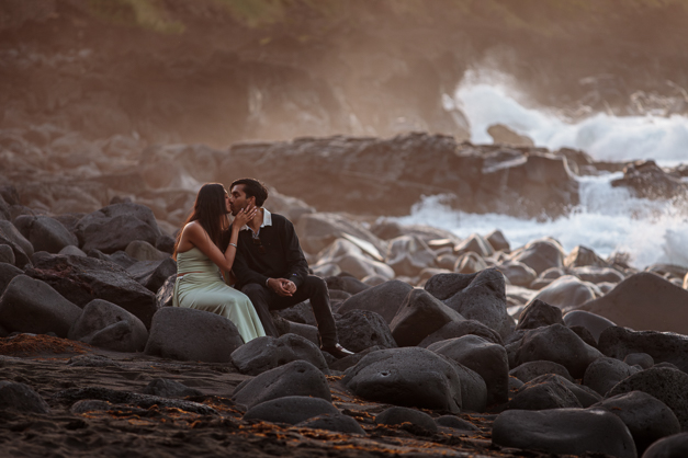 A couple kisses during sunset in front of the ocean during a surprise proposal session in the island of Faial