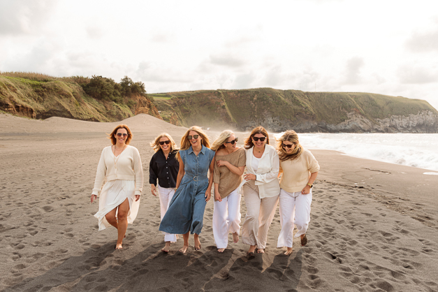 A group of friends walking together and laughing at an empty beach in the Azores