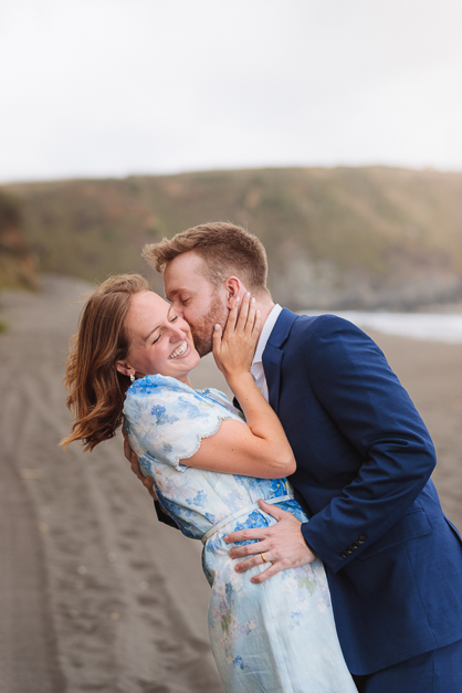 Guy kisses his girlfriend face, both wearing blue tones, during a couple session in the Azores