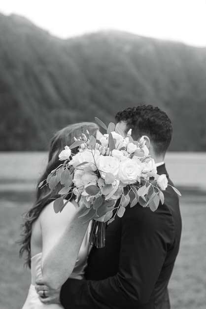 Bride and groom kiss and hide behind her bouquet during an elopement in the Azores