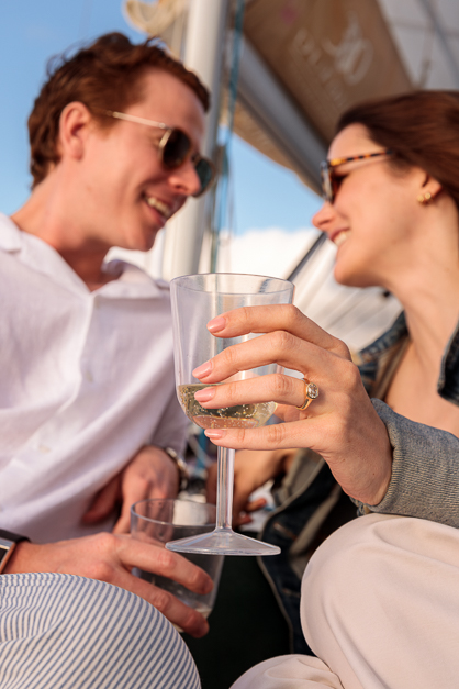 Girl and gur looks at each other while the girl is holding a glass and showing her engagement ring in the Azores