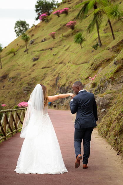 Bride and groom walking a path while the groom kisses his wife's hand during an elopement in the Azores