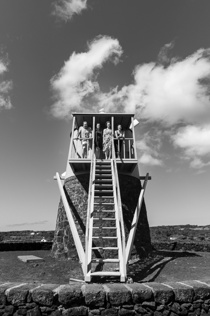 Black and white image of a family posing on an azorean windmill during a family session in the Azores