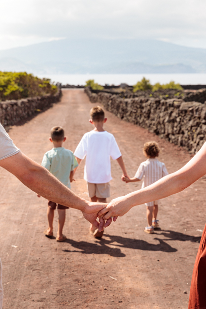 Detail image of the parents' hands holding each other in front of their kids during a family session in the Azores