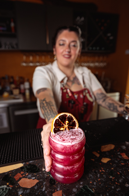 Cocktail woman serves a pink cocktail during a food photography session