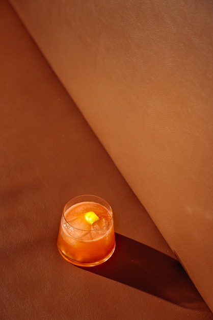 An orange cocktails lays on top of an orange sofa 