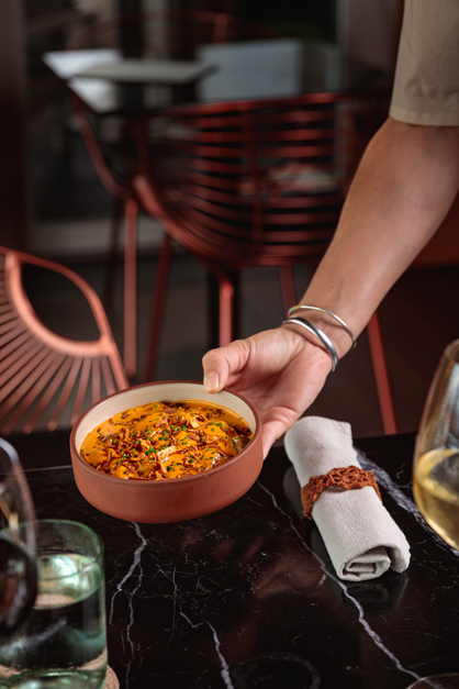 Hand serving a dish over a dark table during a photoshoot in the Azores.
